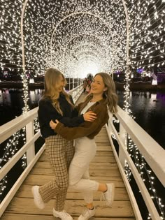 two women hugging on a pier with lights in the background