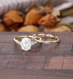 two gold wedding rings sitting on top of a wooden table