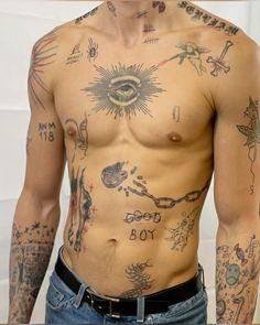 a man with many tattoos on his body and chest is standing in front of a white wall