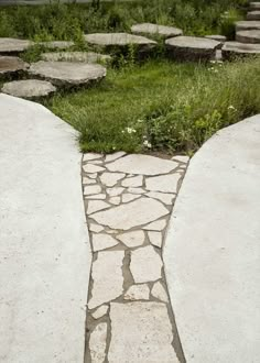 a stone path with grass and rocks in the background