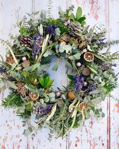 a wreath with greenery and pine cones