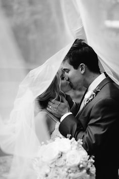 a bride and groom kissing under a veil