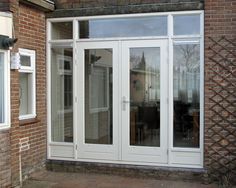 an outside view of a house with sliding glass doors and patio furniture in the yard