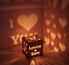 an illuminated cube with the words louise and sam on it in front of a wall