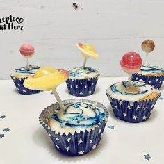 four cupcakes with stars and planets on them