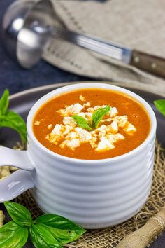 a white bowl filled with soup sitting on top of a plate next to some bread