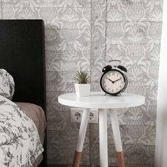 a small white table with an alarm clock on it