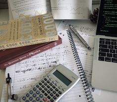 a calculator, notebooks and pen are on top of papers with books