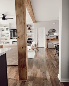 an open kitchen and living room with wood flooring, white walls and ceiling fan