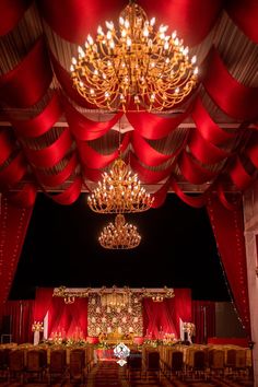 an elaborately decorated banquet hall with chandelier and red drapes on the ceiling