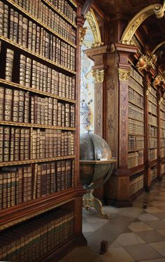 an old library with many books on the shelves and a globe in the middle,