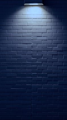 a blue brick wall with a light on it and a window above the door that is lit up