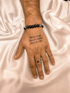 a man's hand with the words written on it and a black beaded bracelet