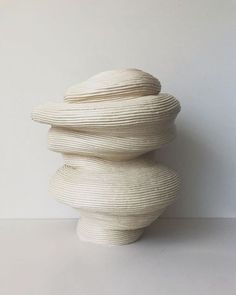 a white sculpture sitting on top of a table next to a wall with no one in it