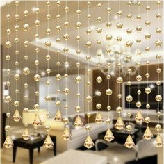 a living room filled with lots of white furniture and hanging glass balls on the ceiling