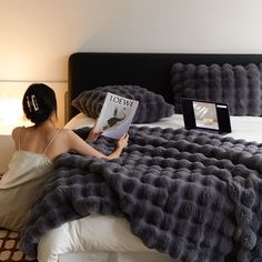 a woman sitting on a bed reading a book