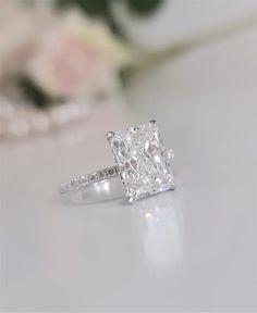 a diamond ring sitting on top of a table next to a bouquet of pink flowers