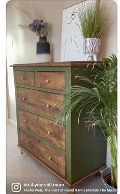 a wooden dresser sitting next to a potted plant