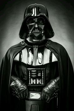 a darth vader is standing in the dark with his hands on his hips