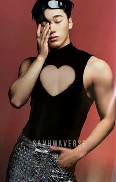 a man in black shirt and silver skirt with heart cut out on his chest posing