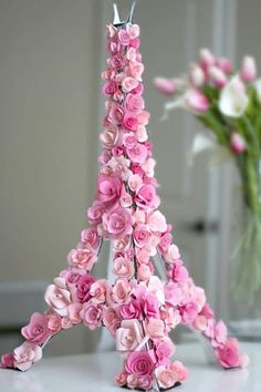 a pink flowered eiffel tower is shown in front of a vase with flowers