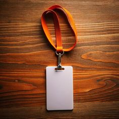 a blank id card attached to a lanyard on a wooden table with an orange strap