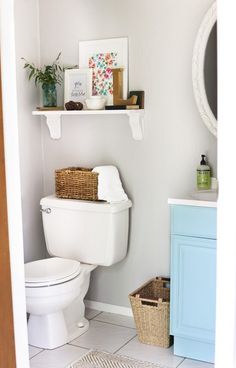 a white toilet sitting in a bathroom next to a blue cabinet and mirror on the wall