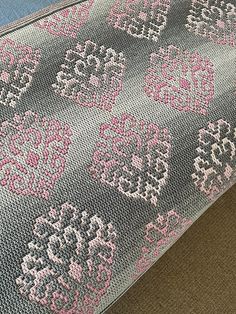 a close up of a rug on the floor with pink and gray designs in it