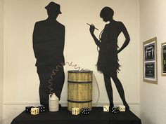 two people standing next to each other in front of a wall with dice on it