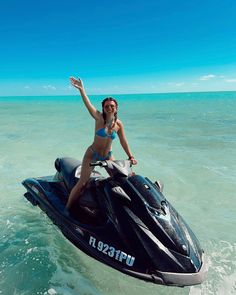 a woman riding on the back of a jet ski in the middle of the ocean