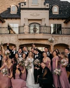 a large group of people standing in front of a building holding bouquets and posing for the camera