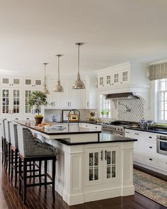 a large kitchen with white cabinets and black counter tops, an island in the middle