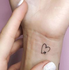 a woman's wrist with a small heart tattoo on the left side of her arm