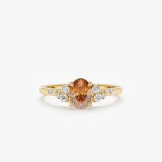 an orange sapphire and diamond ring on a white background