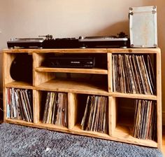 an old record player is sitting on top of a wooden shelf with cd's