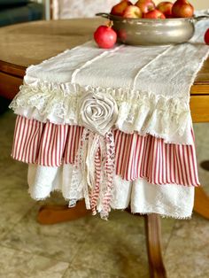 a bowl of apples sitting on top of a wooden table next to a white towel