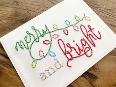 a white card with the words merry christmas lights on it and a string of beads