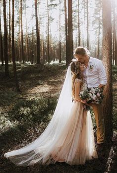 a bride and groom kissing in the woods