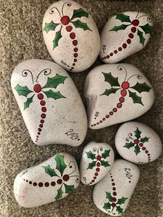 painted rocks with holly leaves and berries on them are arranged in the shape of hearts