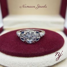 a diamond ring sitting on top of a red velvet cushion in a white gold box