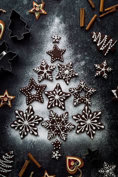 christmas cookies arranged in the shape of a snowflake on a black surface with cinnamon sticks