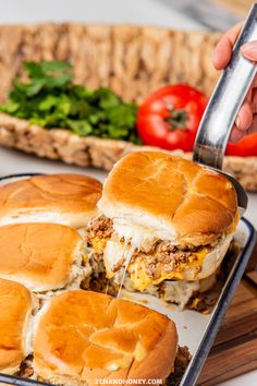 someone is cutting into a sandwich on a tray with other food and vegetables in the background