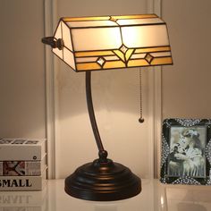 a lamp that is sitting on top of a table next to some books and pictures