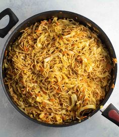 a pan filled with noodles and carrots on top of a table