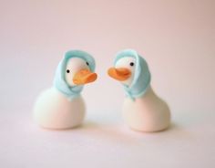 two plastic ducks with blue caps on their heads, one is white and the other is light blue