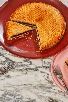 a pie on a red plate next to a pink plate with a slice cut out