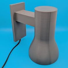 a gray vase sitting on top of a blue surface next to a wall mounted phone charger