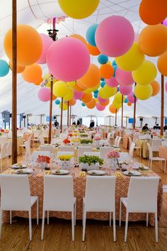 tables and chairs are set up with balloons hanging from the ceiling