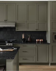 a kitchen with green cabinets and black counter tops, along with an oven in the center