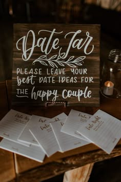 a wooden sign sitting on top of a table next to some candles and paper notes